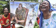Zwei Frauen halten ein Poster von Uhuru Kenyatta und lachen