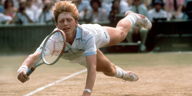 Ein junger Mann mit Tennisschläger hechtet über den Rasenplatz in Wimbledon