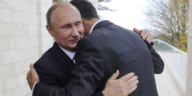 Assad, nur von hinten zu sehen, umarmt Putin demütig