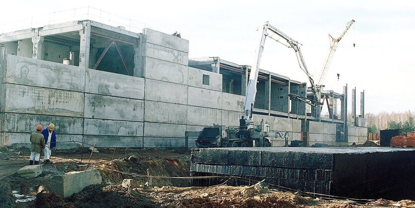 Arbeiter und ein Bagger vor einem Rohbau