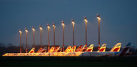 Eine Reihe Flugzeuge der Flotte Air Berlin steht am Abend von Flutlichtern beleuchtet auf einem Feld
