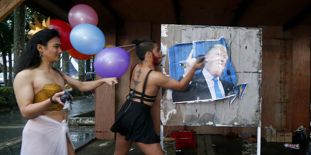 Zwei Mitglieder der LGBT-Community verschmutzen aus Protest ein Plakat von Donald Trump.
