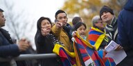 Ein Mann und eine Frau halten Tibet-Fahnen in den Händen und zeigen auf etwas, andere stehen um sie herum