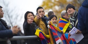 Ein Mann und eine Frau halten Tibet-Fahnen in den Händen und zeigen auf etwas, andere stehen um sie herum