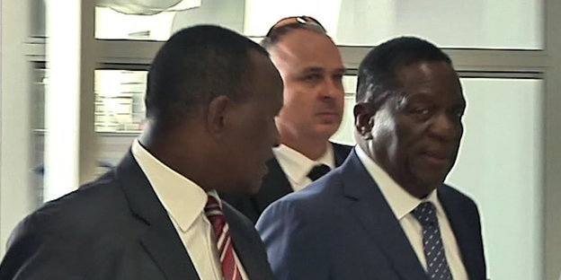 Emmerson Mnangagwa geht im dunkelblauen Anzug und mit ernstem Gesicht