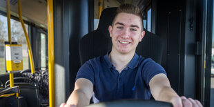 Busfahrer Lionel Oehlke sitzt lachend in einem BVG-Bus.