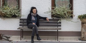 Irmgard Kolbe sitzt auf einer Bank vor ihrem Haus