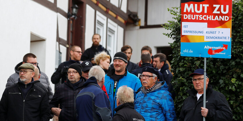 Menschen stehen vor einem Fachwerkhaus