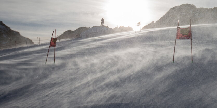 Wind wirbelt Schnee auf einer Skipiste auf