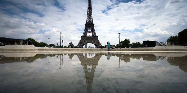 Der Eiffelturm spiegelt sich in einer Pfütze.
