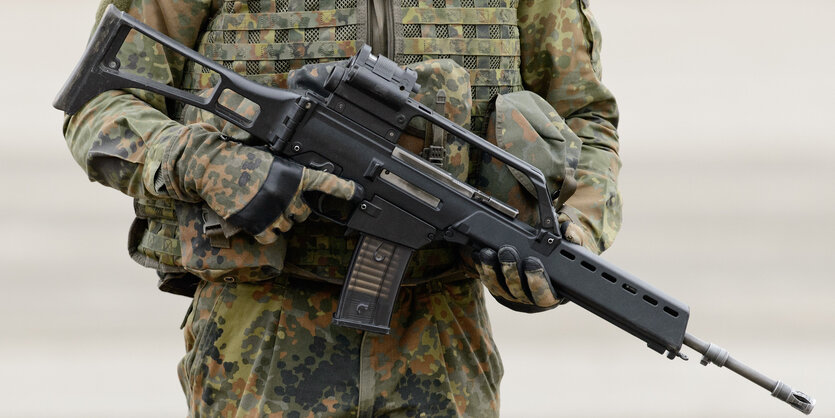 Eine Person in Uniform hält ein Sturmgewehr