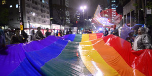 Viele Menschen halten eine extrem große Regenbogenfahne