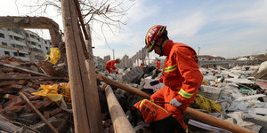 Ein Feuerwehrmann sucht in den Trümmern nach Verletzten