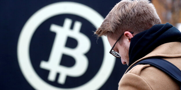 Ein Mann vor dem Bitcoin-Symbol