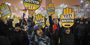 Demontranten halten Schilder hoch, auf denen auf Rumänisch „Alle für Gerechtigkeit“ steht