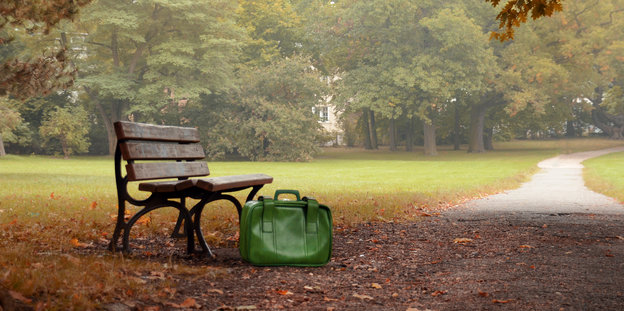 Eine Parkbank, davor eine grüne Tasche