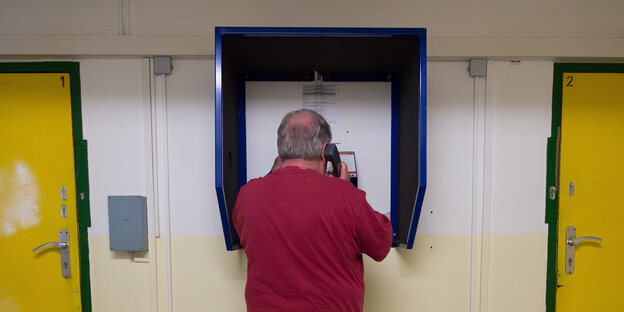 Ein Mann benutzt eine Telefonzelle zwischen zwei Türen