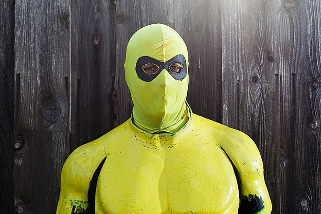 Ein Mensch in eine grün-gelben Superheldenkostüm samt Gesichtsmaske