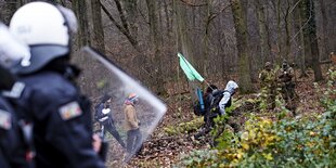 Behelmte Polizisten und vermummte Demonstranten