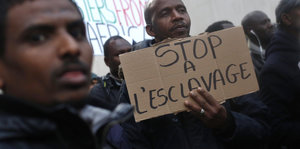 Zwei Männer halten ein Schild mit der Aufschrift "Stop a l'esclavage"