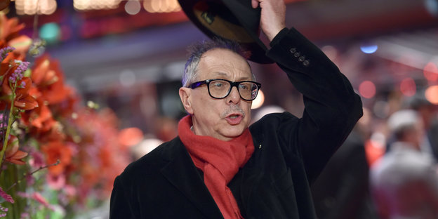 Dieter Kosslick nimmt seinen Hut ab, im Hintergrund verschwommen Berlinaletrubel