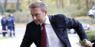 Ein Mann mit kurzen blonden Haaren und in Anzügen eilt durch das Bild, es ist Christian Lindner