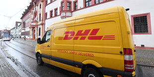 Ein Auslieferungswagen des Paketdienstes DHL fährt vorbei.