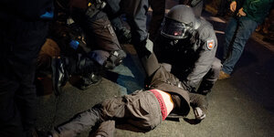 Polizisten drücken gewaltsam eine Person zu Boden