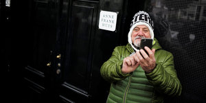 Ein Mann steht vorm Anne-Frank-Haus und macht ein Selfie