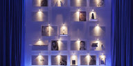 Fotos hängen an einer blau beleuchteten Wand