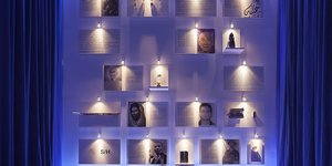 Fotos hängen an einer blau beleuchteten Wand