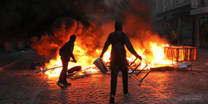 Zwei Menschen stehen vor brennenden Barrikaden