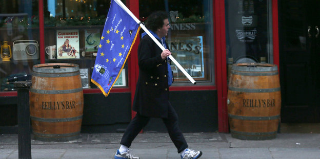 Ein Mann läuft durch Dublin mit einer Flagge in der Hand, die der der EU ähnelt