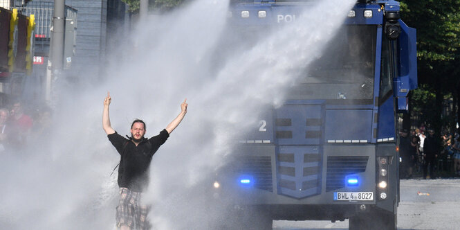 Ein Demonstrant stellt sich im Bereich der Reeperbahn in Hamburg einem Wasserwerfer entgegen