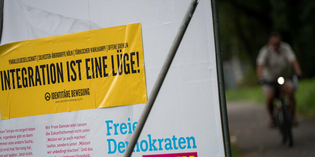 ein gelber Aufkleber der Identitären, der auf einem FDP-Wahlplakat klebt. Darauf steht „Integration ist eine Lüge“