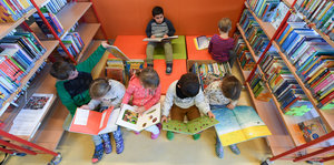 Schüler mit Büchern zwischen Bücherregalen