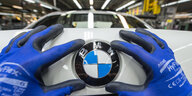 Behandschuhte Hände montieren ein BMW-Emblem auf ein Auto