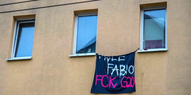 An einem Haus hängt ein Transparent: „Fabio FCK G20“