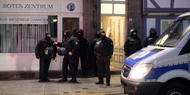 Vermummte Polizisten stehen vor einem Haus