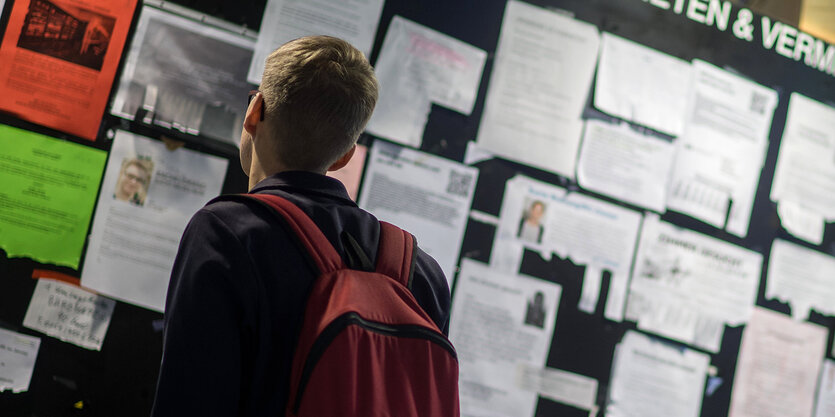 Ein Student guckt am Schwarzen brett nach Wohnungen