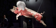 Bei einer Kunstausstellung: Ein künstlicher Schweinekadaver mit weißen Engelsflügeln scheint in der Luft zu schweben