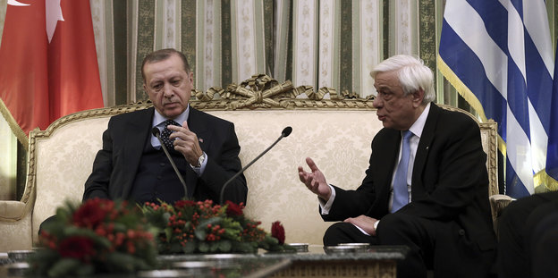 Der türkische Präsident Erdoğan sitzt beim Besuch in Athen mit Griechenlands Präsident Prokopis Pavlopoulos auf einem crèmefarbenen Sofa, Pavlopoulos spricht und gestikuliert