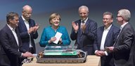 Angela Merkel, Stanislaw Tillich und andere stehen im Halbkreis und klatschen in die Hände