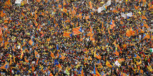 Eine Menschenmenge demonstriert. Viele tragen Katalonien-Flaggen