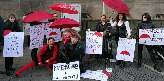 Sexarbeitende posieren mit Schildern und roten Regenschirmen vor dem Rathaus Schöneberg