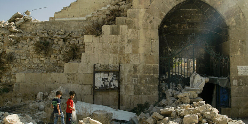 Zwei kleine Jungs mit Müllsäcken vor Trümmern in Aleppo