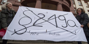 Menschen halten ein Banner auf dem der durchgestrichene Schriftzug "§219a" steht