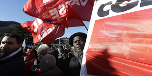 Rote Fahnen und ein Mann, der ein rotes Transparent hält, in einer Demo