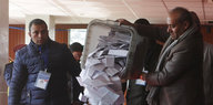 Ein Mann leert eine Wahlurne aus