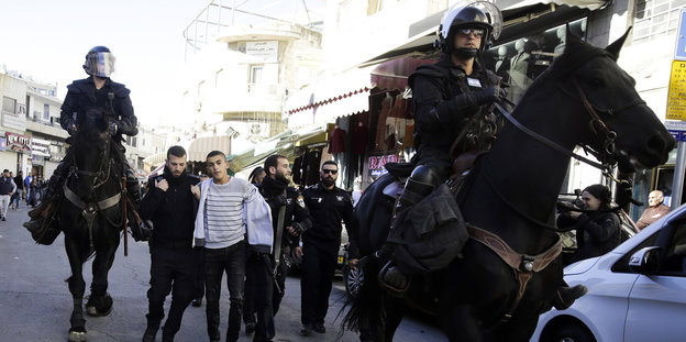 Istraelische Polizisten auf Pferden führen Palästinenser ab